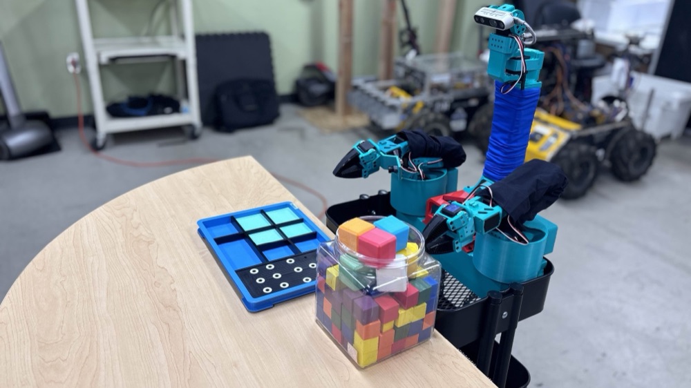 The XLeRobot-Pro bimanual mobile robot at a table with colored blocks